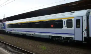 Biało-niebieski, komfortowy wagon kolejowy PKP Intercity z żółtym pasem, numerem "1" i klimatyzacją, gotowy do podróży.