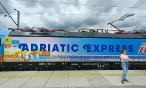 Kobieta na tle lokomotywy "Adriatic Express", która zabierze ją pociągiem do Chorwacji.