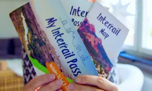 Ręce trzymają broszurę "My Interrail Pass" i mapę. To świetny sposób na podróżowanie po Europie, jeśli zastanawiasz się interrail co to.
