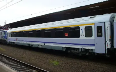 Biało-niebieski, komfortowy wagon kolejowy PKP Intercity z żółtym pasem, numerem "1" i klimatyzacją, gotowy do podróży.