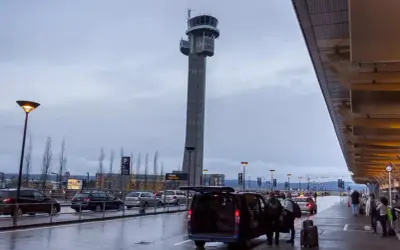 Wieża kontrolna na oslo lotnisko. Ludzie z bagażami wsiadają do vana.