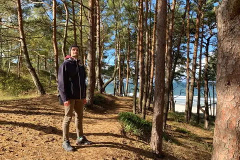 Mężczyzna w lesie sosnowym na Jastrzębiej Górze, z widokiem na morze. Piękne połączenia natury i krajobrazu.