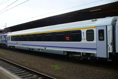 Biało-niebieski, komfortowy wagon kolejowy PKP Intercity z żółtym pasem, numerem "1" i klimatyzacją, gotowy do podróży.