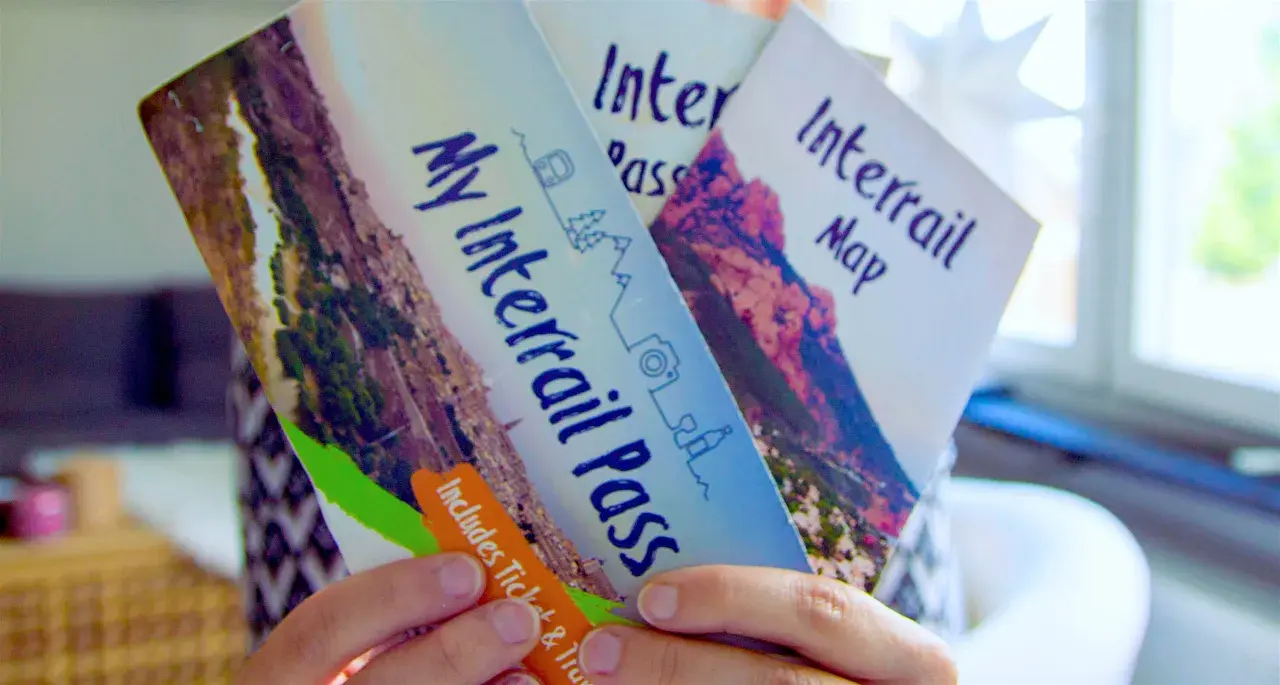 Ręce trzymają broszurę "My Interrail Pass" i mapę. To świetny sposób na podróżowanie po Europie, jeśli zastanawiasz się interrail co to.