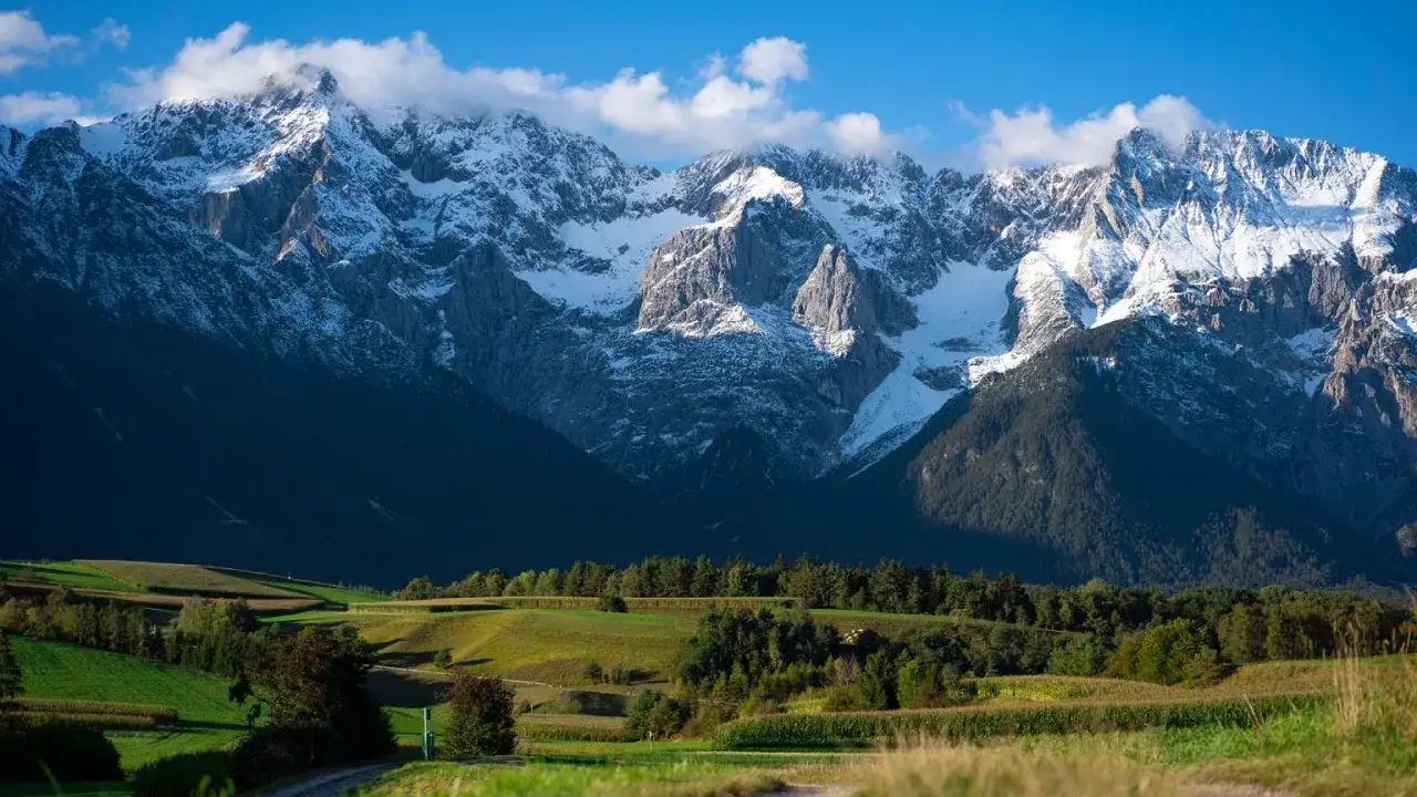 Gdzie jest Tyrol? Widać tu ośnieżone szczyty górskie, zielone pola i lasy.