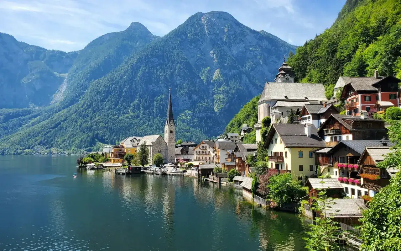 Malownicze domy nad jeziorem, w tle góry i kościół. To Hallstatt, gdzie znajduje się słynna kopalnia soli.