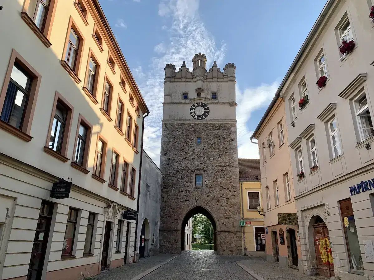 Kamienna wieża z zegarem w centrum miasta Igława, otoczona zabytkowymi kamienicami.