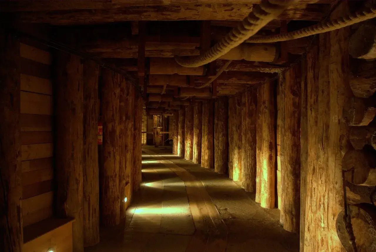 Drewniany tunel w kopalni soli Hallstatt, oświetlony punktowo, tworzy tajemniczą atmosferę.