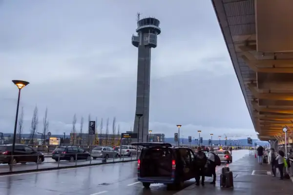 Wieża kontrolna na oslo lotnisko. Ludzie z bagażami wsiadają do vana.
