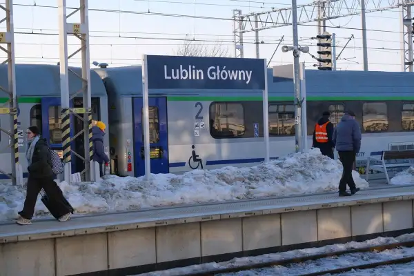 Zimowy dzień na stacji Lublin Główny. Pasażerowie z bagażami czekają na pociąg, a śnieg zalega na peronie.